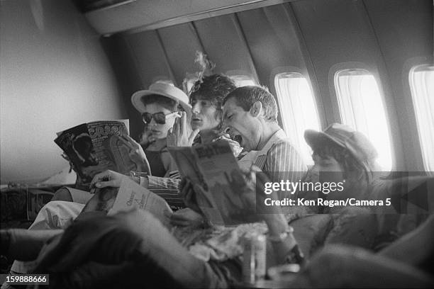 Ronnie Wood, Charlie Watts and Keith Richards of the Rolling Stones with Bianca Jagger are photographed reading on their plane in 1975 in Kansas...