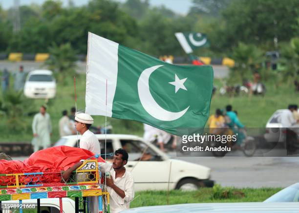 Pakistani people take part in the celebrations marking Pakistan's 76th Independence Day anniversary as they hold flag in Rawalpindi, Pakistan, on...
