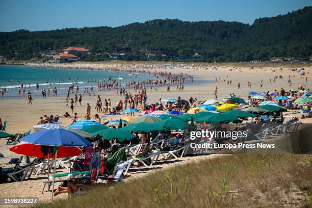 Several people take shelter from the sun under umbrellas on August 7 in Pontevedra, Galicia, Spain. High temperature alerts will begin Monday...