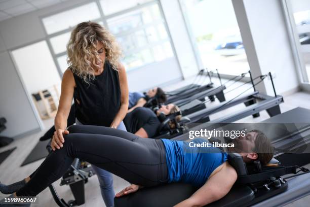 pilates studio gym: women on reformer machine - reformer stock pictures, royalty-free photos & images