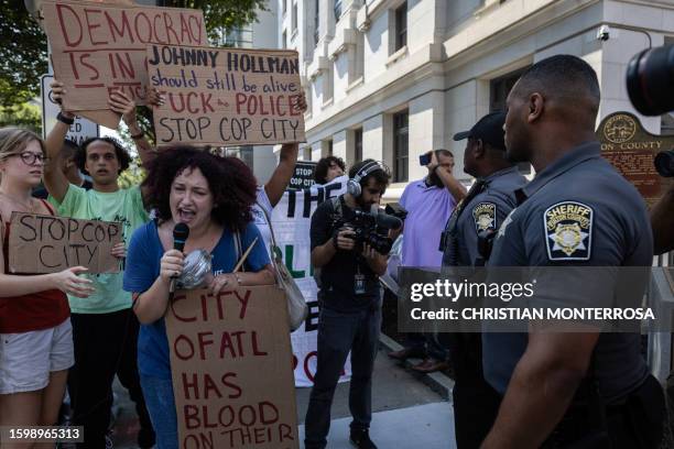 Police officers watch as protesters of "Cop City" approach the Lewis R. Slaton Courthouse ahead of an expected indictment of former President Donald...