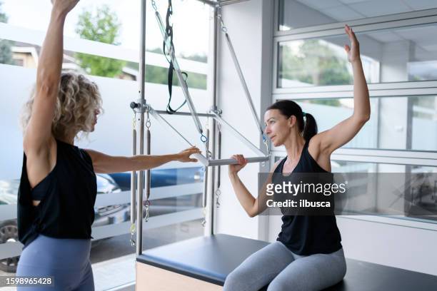 pilates-studio-fitnessstudio: frau mit trapez-tischmaschine - trapezstange stock-fotos und bilder