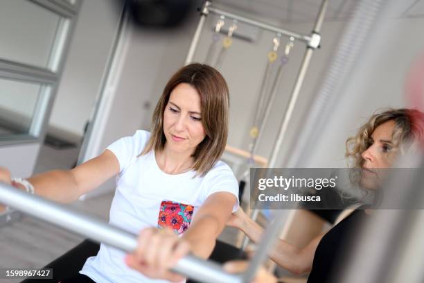 pilates-studio-fitnessstudio: frau mit trapez-tischmaschine - trapezstange stock-fotos und bilder