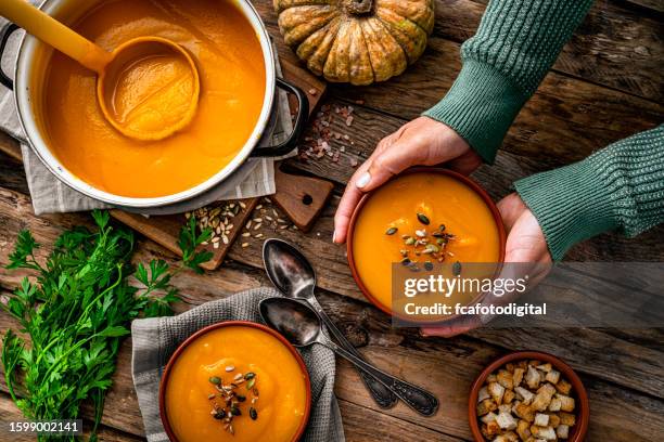 femme servant deux bols de soupe à la citrouille pour le repas de thanksgiving - recette photos et images de collection