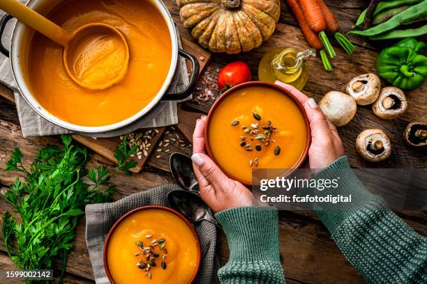 woman holding a bowl of pumpkin soup for thanksgiving meal - pompoen stockfoto's en -beelden