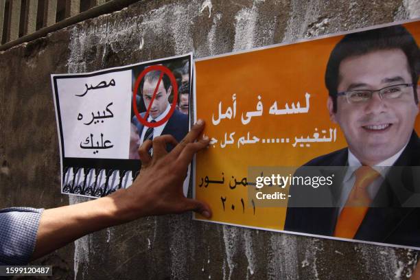 An Egyptian supporter of opposition leader Ayman Nur glues an anti Gamal Mubarak , son of Egyptian President Hosni Mubarak, poster with the writing...