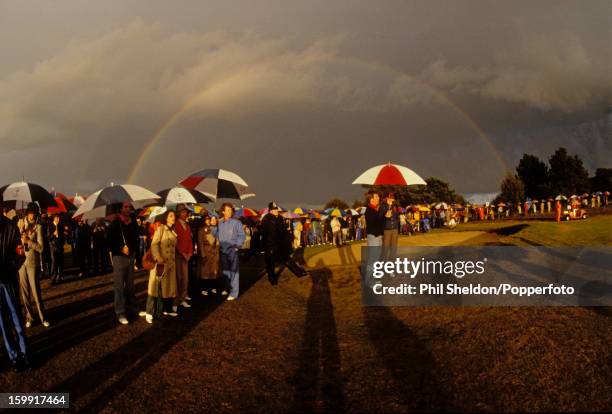 Oblivious to the rainbow behind them, American golfers Jerry Pate, Tom Watson and Ben Crenshaw with their wives shelter from a rainstorm during the...