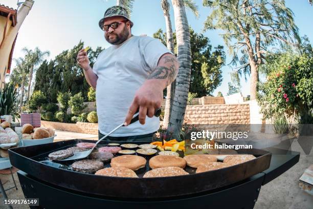 man snacking while cooking food on a grill - spatula stock pictures, royalty-free photos & images