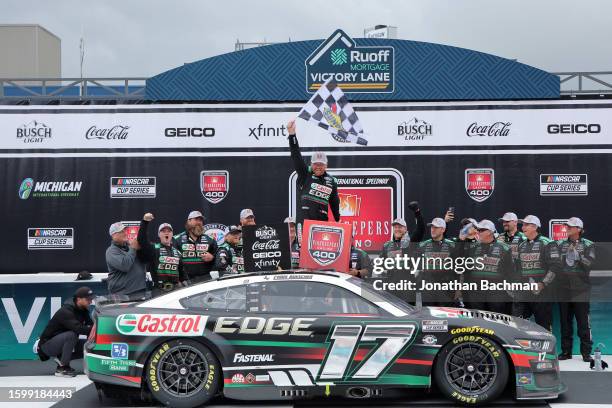 Chris Buescher, driver of the Castrol Edge Ford, waves the checkered flag in victory lane after winning the NASCAR Cup Series FireKeepers Casino 400...