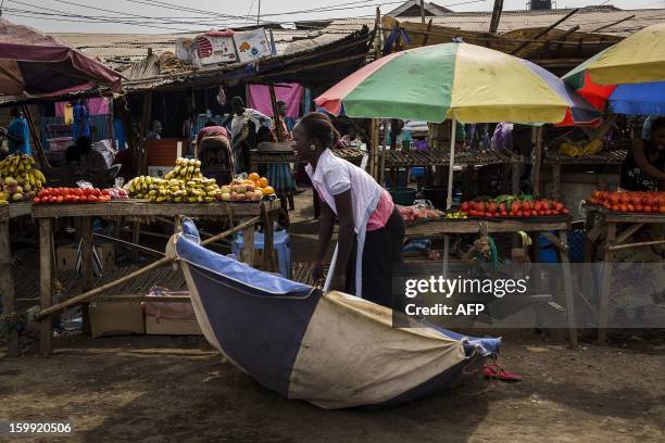 South Sudanese woman picks up her parasol felled by the wind next to her fruit and vegetables stand at Gudele market in Juba, South Sudan January 23,...