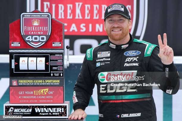 Chris Buescher, driver of the Castrol Edge Ford, celebrates in victory lane after winning the NASCAR Cup Series FireKeepers Casino 400 at Michigan...