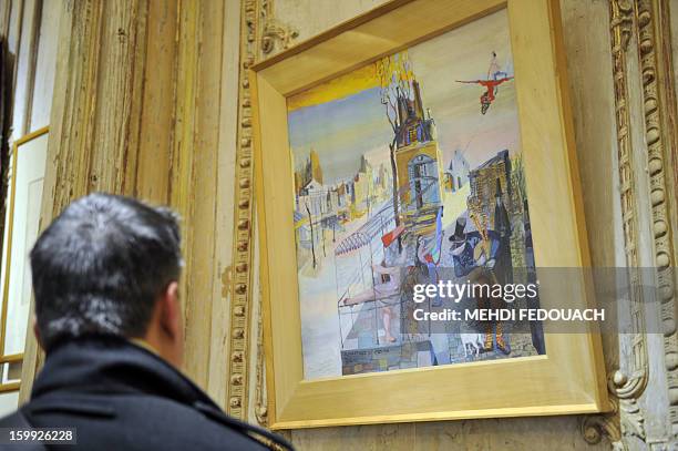 Man looks at a gouache painting by Alexandre Trauner ahead of an auction in Paris on January 23, 2013 of a unique collection containing over 5000...