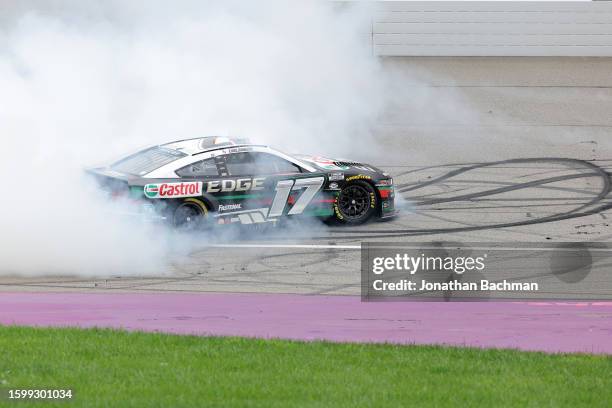 Chris Buescher, driver of the Castrol Edge Ford, celebrates with a burnout after winning the NASCAR Cup Series FireKeepers Casino 400 at Michigan...
