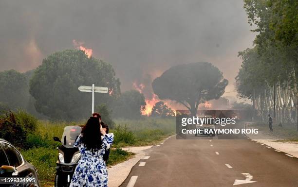 Woman takes a picture of a wildfire that broke out leading to the evacuation of more than 3.000 people from nearby campsites in Saint-Andre near...