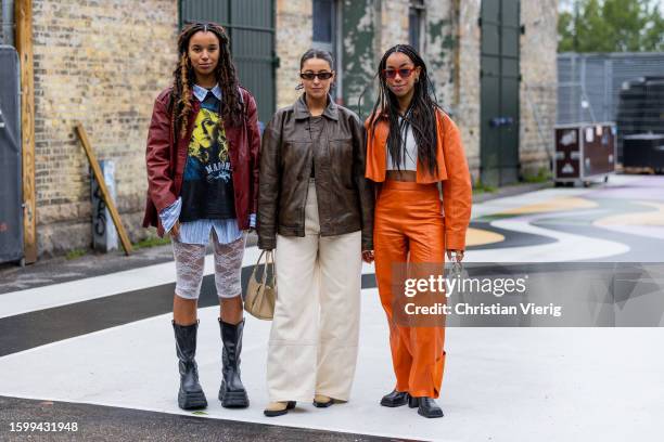 Fia Hamelijnck wears red jacket, white laced skirt, blue white oversized button shirt, black boots & Benthe Liem wears brown leather jacket, beige...