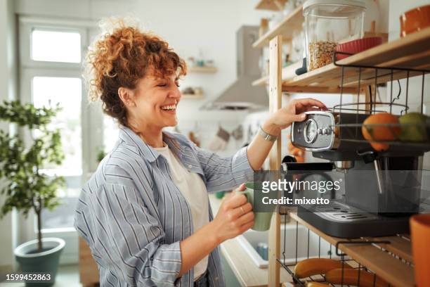 young beautiful smiling woman making coffee in a domestic kitchen - coffee machine stock pictures, royalty-free photos & images