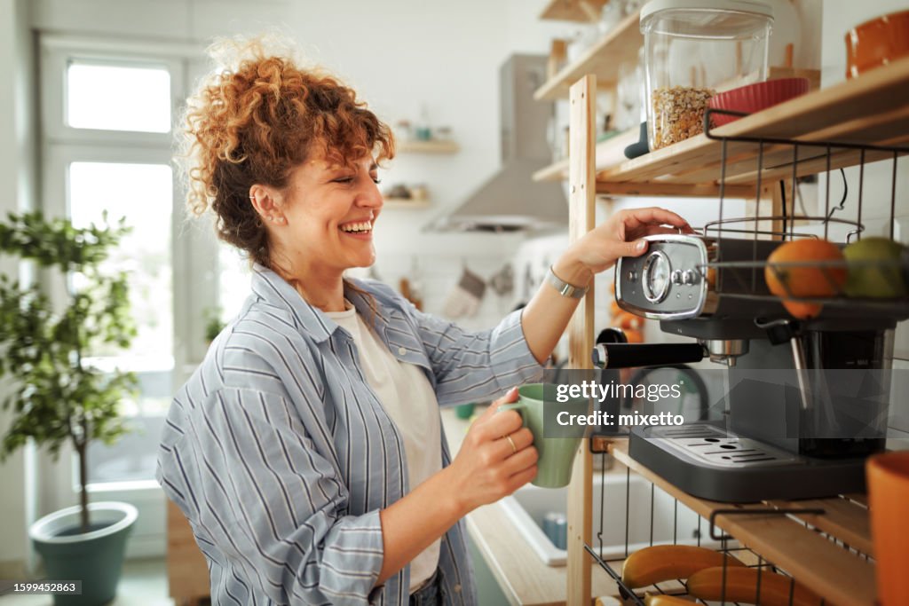 Young beautiful smiling woman making coffee in a domestic kitchen