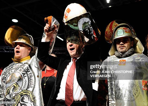 French far-left Parti de Gauche party's leader Jean-Luc Melenchon holds a steelmaker helmet with his portrait drawn on it which he was offered by...