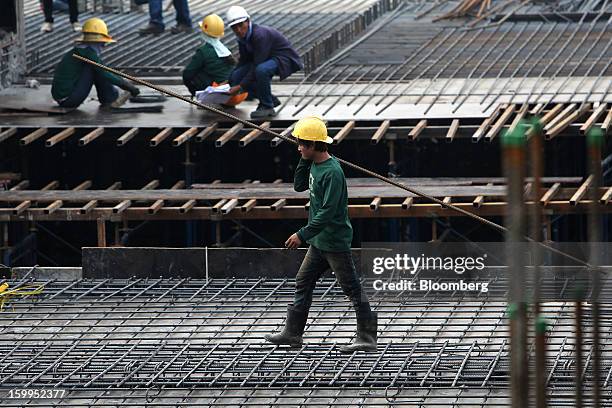 Construction worker carries materials on a building site at Siam Square in Bangkok, Thailand, on Wednesday, Jan. 23, 2013. Prime Minister Yingluck...