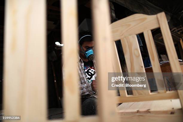 Carpenter wearing a face mask finishes chairs at a workshop in Bangkok, Thailand, on Wednesday, Jan. 23, 2013. Prime Minister Yingluck Shinawatra's...