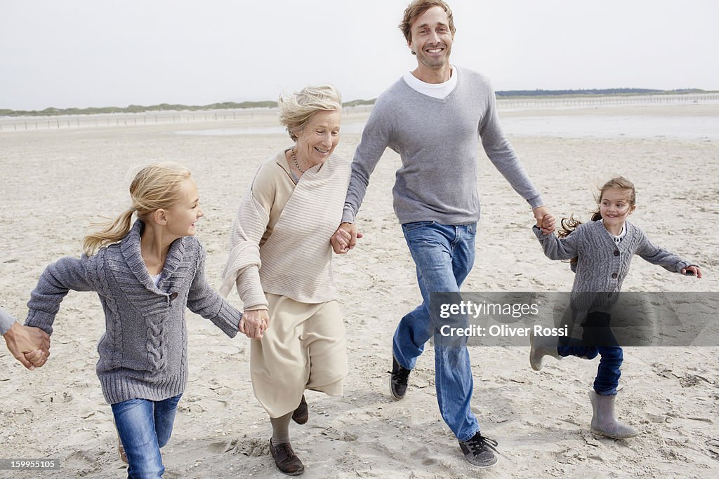 Happy family with grandmother running on the beach