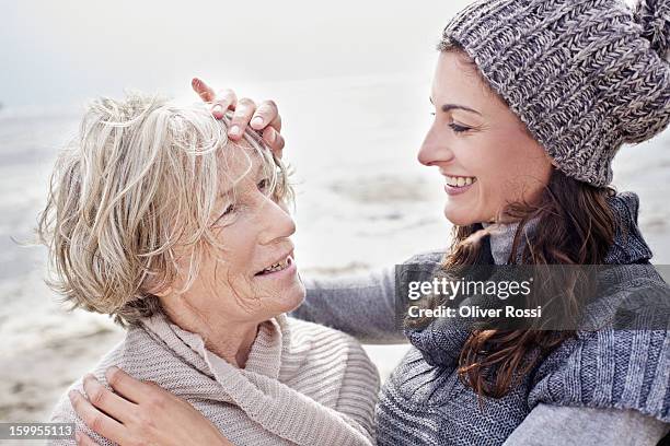 senior woman and adult daughter on the beach - leanincollection mother stock pictures, royalty-free photos & images