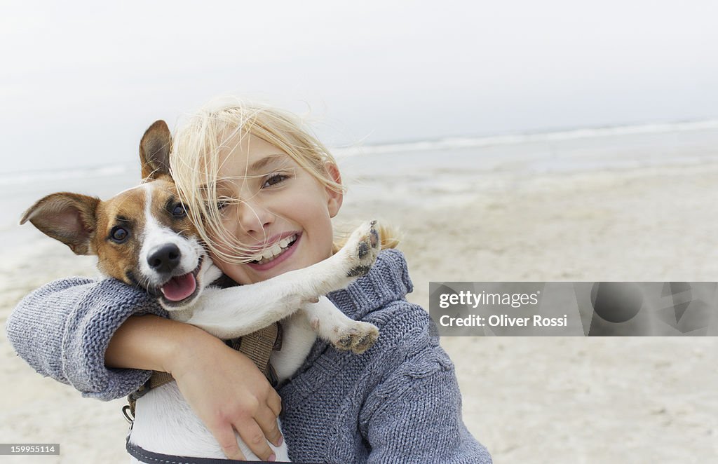 Happy girl hugging dog on the beach, portrait