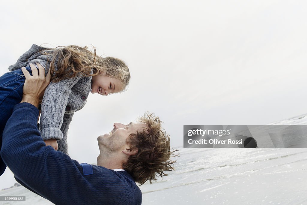 Father carrying daughter on the beach