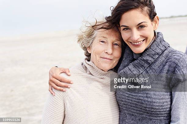 senior woman and adult daughter on the beach - daughter stock-fotos und bilder