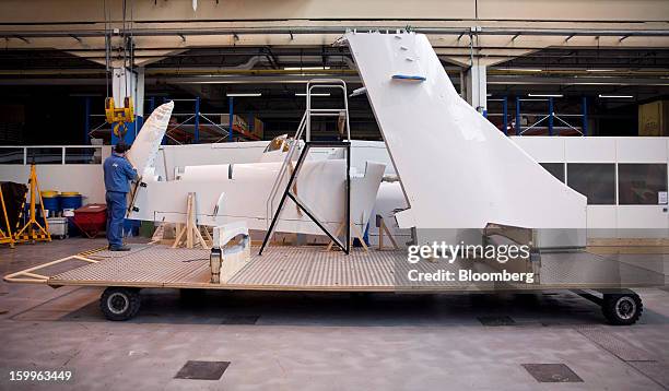 An employee prepares tailfin components during the construction of an ATR-72 turboprop aircraft, manufactured by Avions de Transport Regional , at...