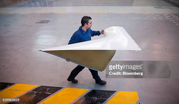 An employee carries a section of fuselage during the construction of an ATR-72 turboprop aircraft, manufactured by Avions de Transport Regional , at...