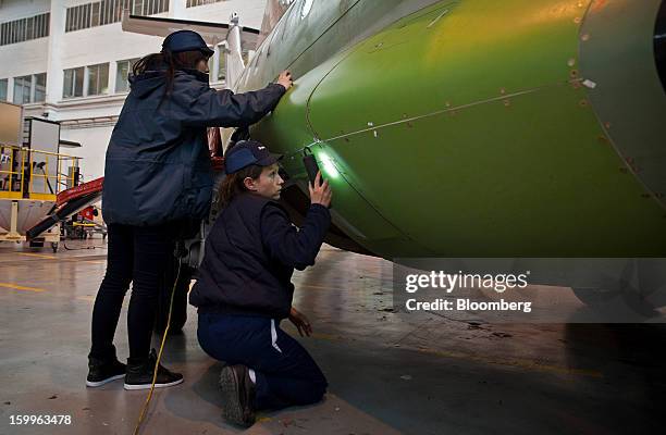 Employees check the fuselage of an ATR-72 turboprop aircraft, manufactured by Avions de Transport Regional , during assembly at the company's...