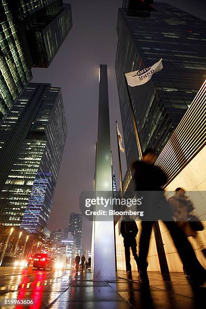 Pedestrians walk past Samsung Electronics Co.'s offices as the company's corporate flag flies in Seoul, South Korea, on Wednesday, Jan. 23, 2013....