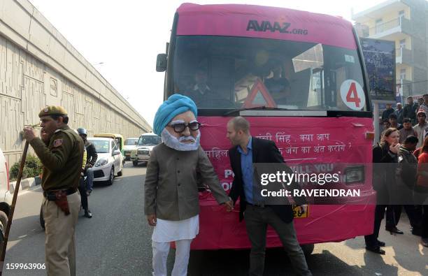 Man dressed as Indian Prime Minister Manmohan Singh stands in front of the 'Pink Bus' which launched the Campaign for Education as the solution to...