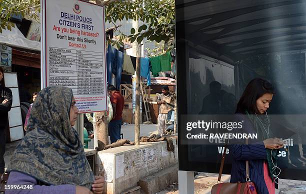 Indian commuters stand in front of a Delhi police notice board at the Munirka bus stand in New Delhi on 24 January, 2013. After one month of lurid...