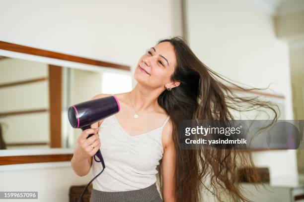 家でヘアドライヤーで髪を乾かす若い女性 - hair dryer ストックフォトと画像