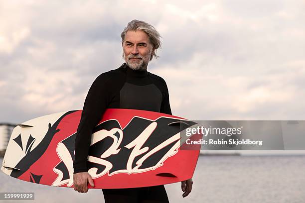 mature man in wetsuit walking with kitesurf board - kite surfing stock pictures, royalty-free photos & images