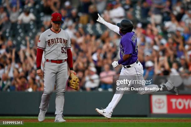 Elehuris Montero of the Colorado Rockies celebrates as he runs past Christian Walker of the Arizona Diamondbacks after hitting a fifth inning solo...