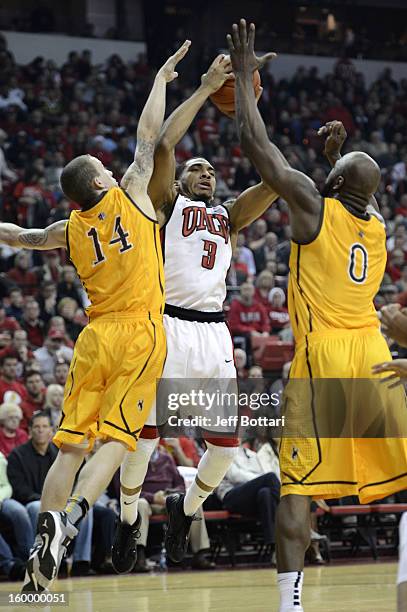 Anthony Marshall of the UNLV Rebels drives to the basket against Josh Adams and Leonard Washington of the Wyoming Cowboys at the Thomas & Mack Center...