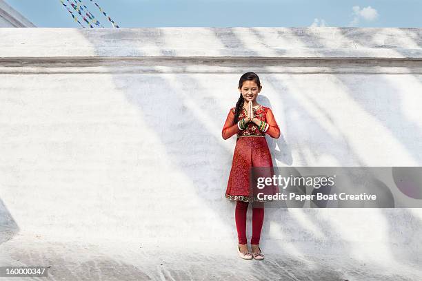 girl by a white wall doing namaste hand gesture - prayer pose greeting fotografías e imágenes de stock