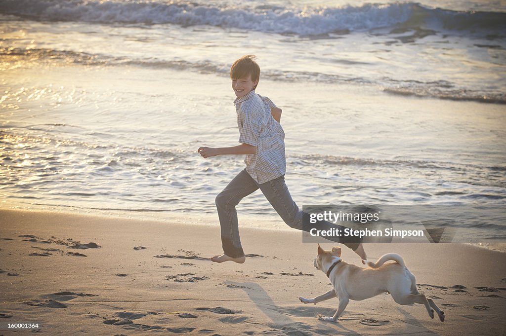 Boy and his dog running on the beach