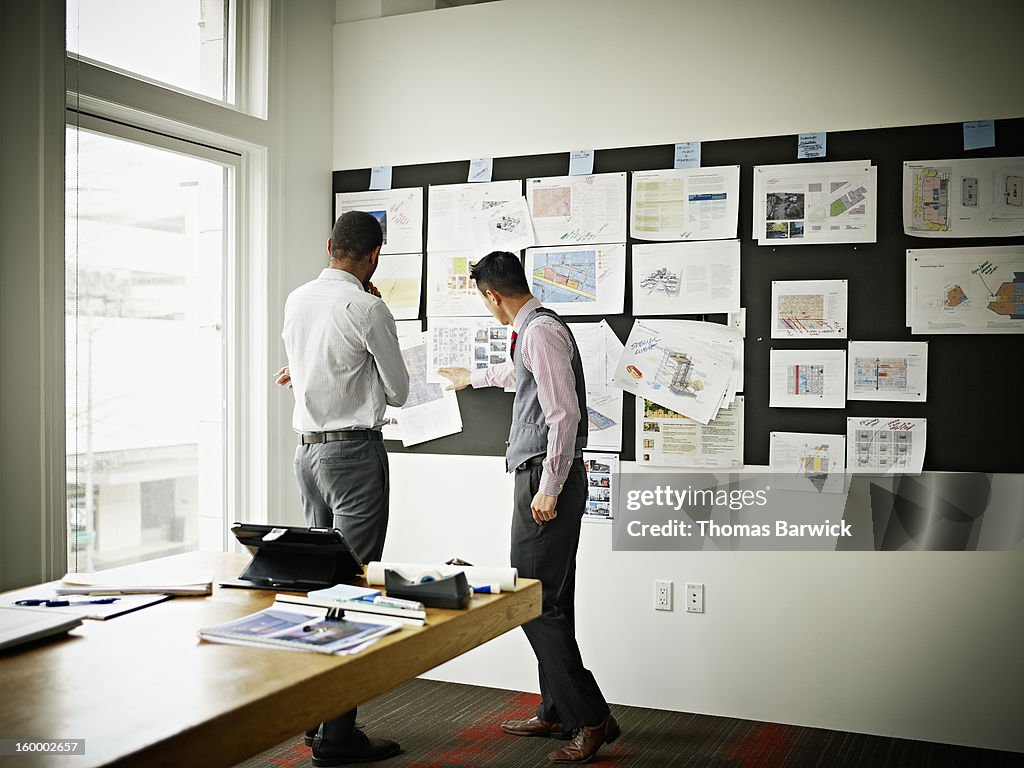 Coworkers examining project on board in office