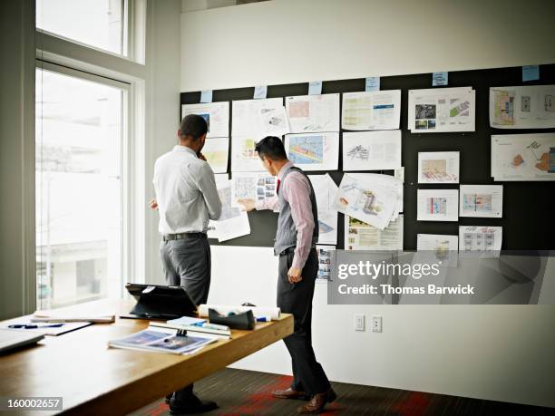 coworkers examining project on board in office - 2 people back asian imagens e fotografias de stock