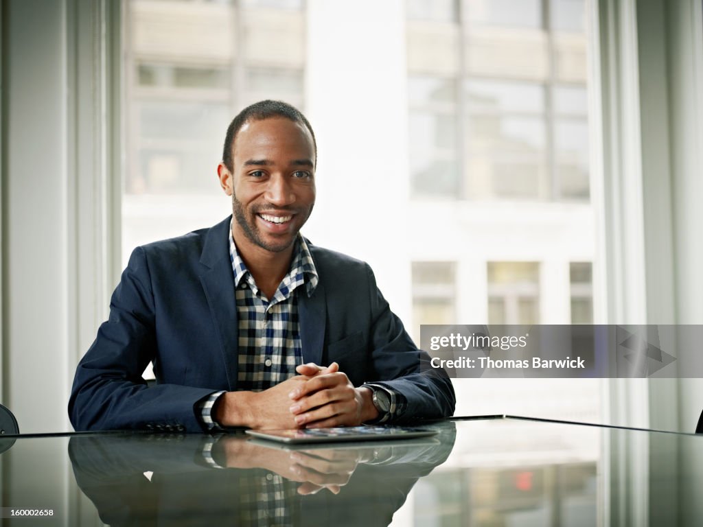 Smiling businessman sitting at conference table