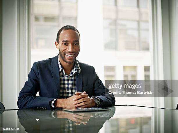 smiling businessman sitting at conference table - meeting room - fotografias e filmes do acervo