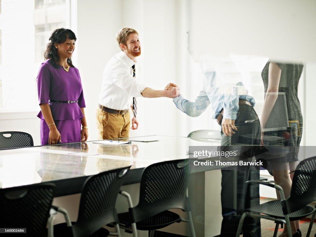 Two businessmen shaking hands across office table