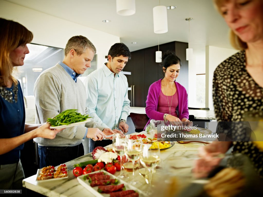 Mature couples preparing food in home kitchen