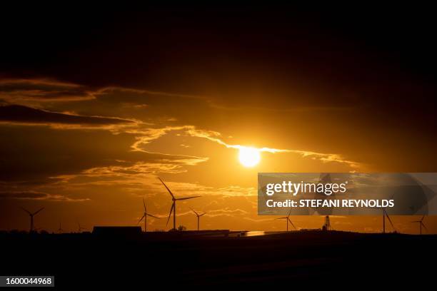 Wind turbines are seen at sunset in Williamsburg, Iowa, on August 14, 2023.