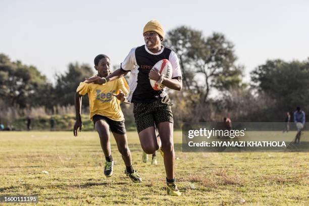 Lwazi Tshazi runs with the ball followed by Siyabonga Mosemini during a rugby practice at Jabulani Technical Secondary School in Soweto on May 25,...