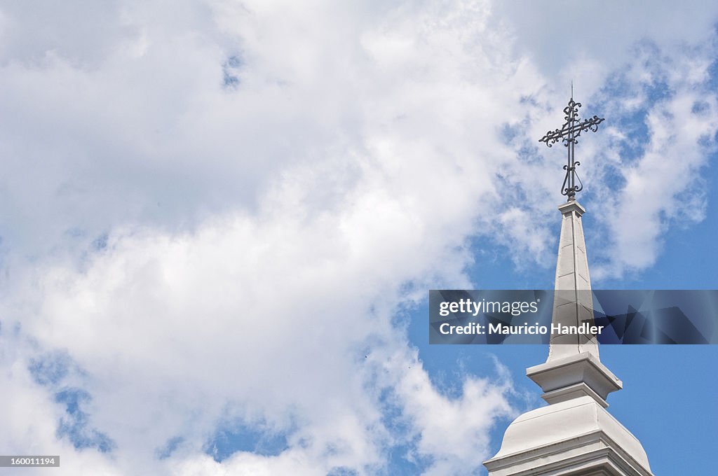 A church steeple against a blue sky with clouds.